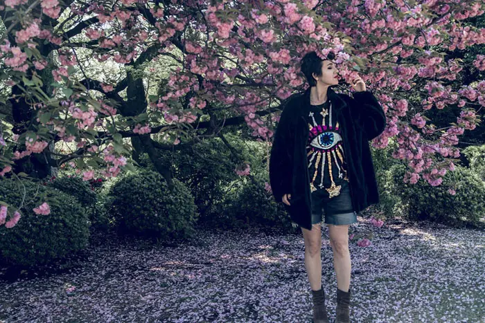 Woman under cherry blossoms wearing Japanese-inspired streetwear – ARASHI harmony of motion and color